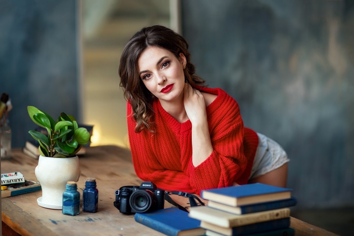 Woman in red sweater with camera and books
