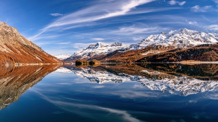 Snow-capped Alps reflected in a calm lake in Switzerland