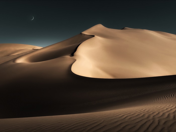 Desert sand dunes under a crescent moon