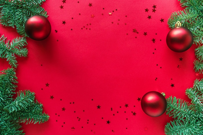 Christmas ornaments and fir branches on red background