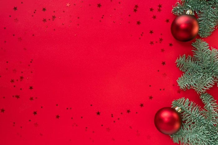 Christmas ornaments and fir branches on red background