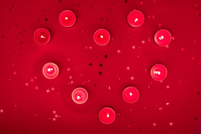 Heart-shaped arrangement of red candles and star confetti