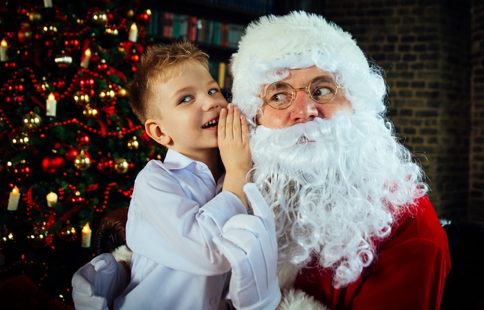 Boy Whispering to Santa Claus by Christmas Tree