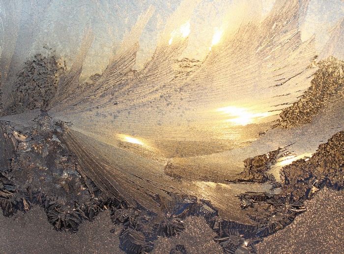Frost patterns on a window with sunlight