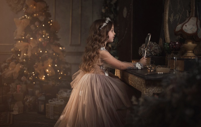 Girl in elegant dress by Christmas tree
