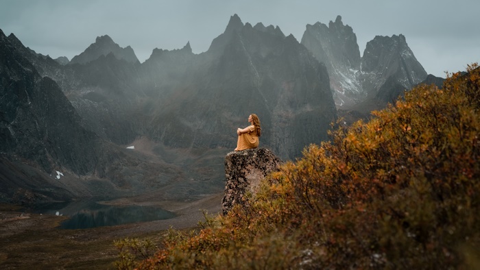 Woman sitting on a rock overlooking mountains