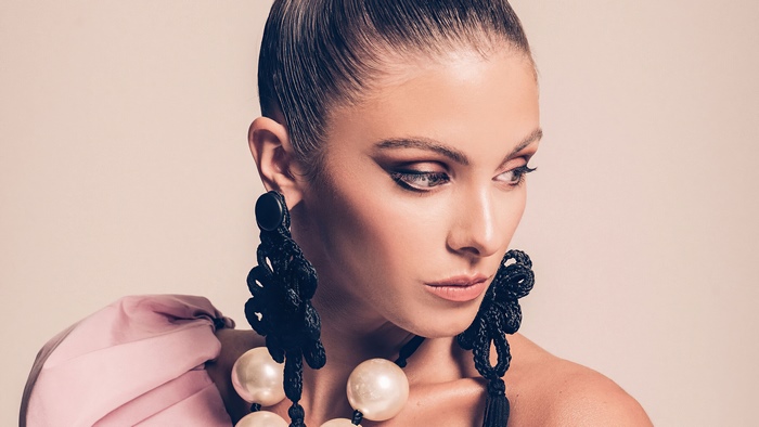 Carmella Rose wearing large black earrings and a pink top