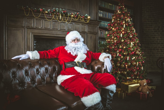 Santa Claus sitting on a couch by a Christmas tree