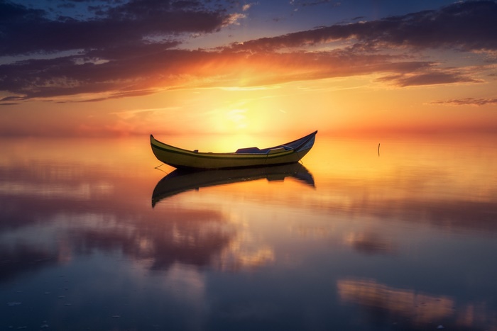 Boat on a calm lake at sunset with reflection