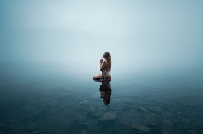 Woman praying in a foggy lake