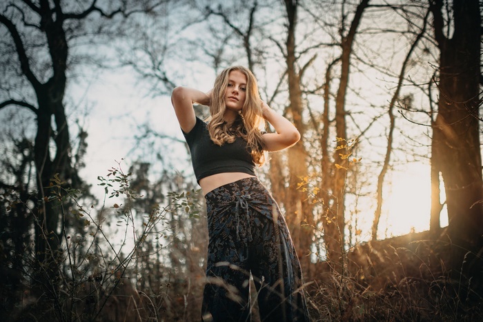 Blonde woman posing in a forest at sunset