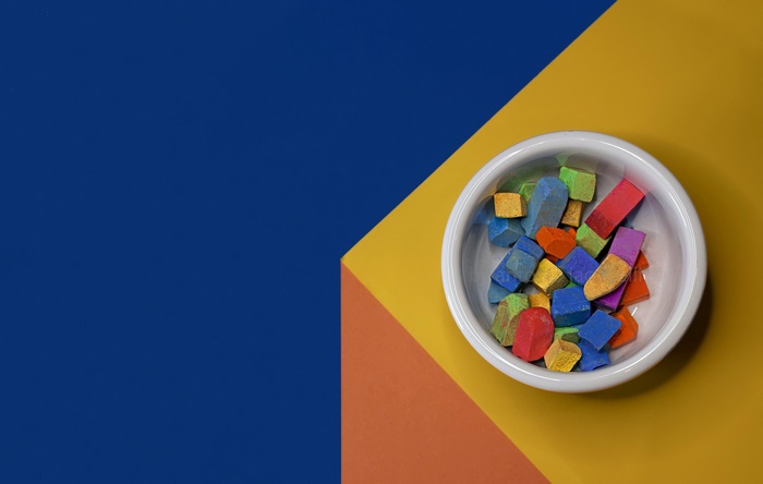 Bowl of colorful chalk pieces on a geometric background