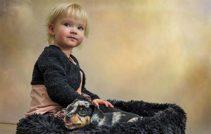 Young girl with a puppy in a fluffy bed