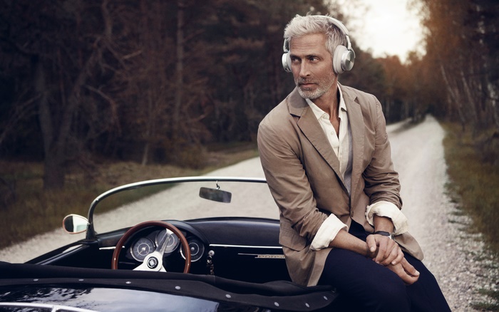 Man with headphones sitting on a vintage car