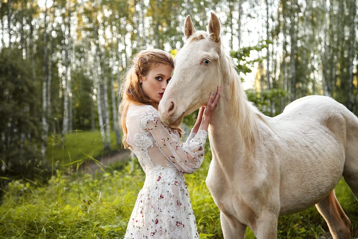 Woman in white dress with horse in forest