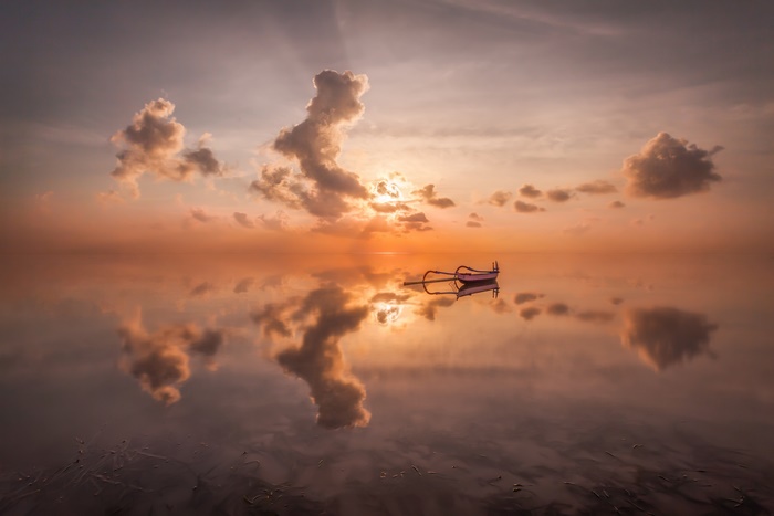 Boat on calm sea during sunset with reflection