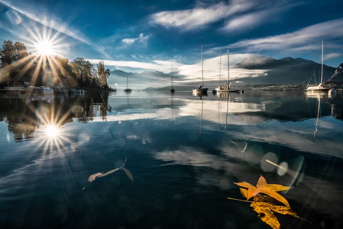 Sailboats on a lake with sunbeams and mountains