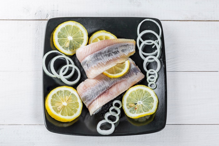 Herring fillets with lemon and onion on a plate
