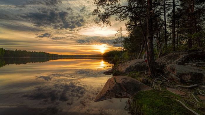 Sunset over a lake with pine trees and rocks