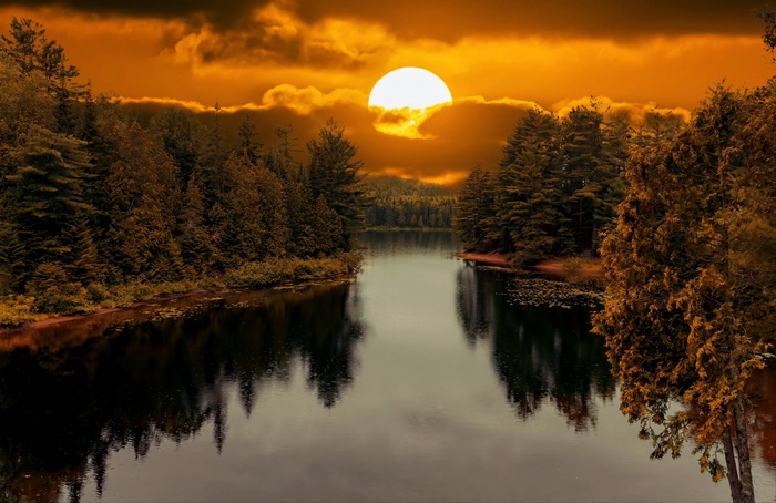 Sunset over a forest lake with reflections