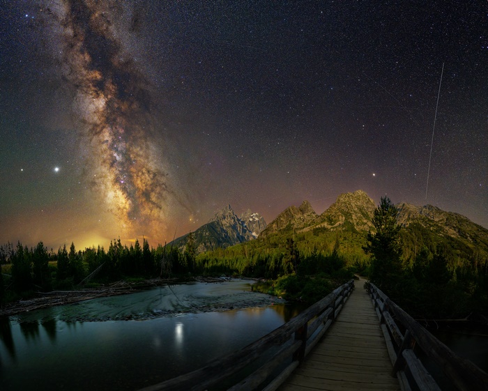 Bridge over river under Milky Way and mountains