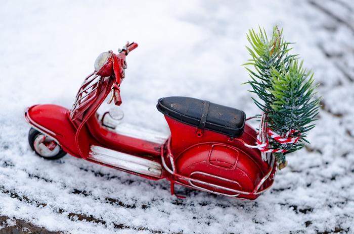 Red toy moped with Christmas tree in snow