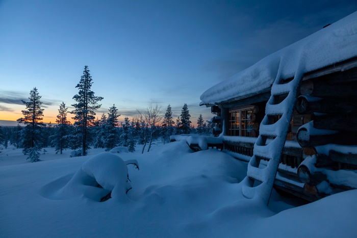 Snowy cabin in Finland at sunset