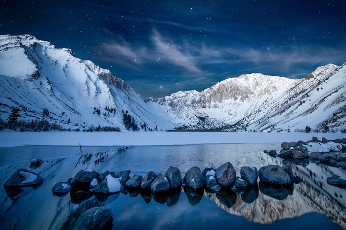 Snowy Mountains Reflecting in a Frozen Lake Under a Starry Sky