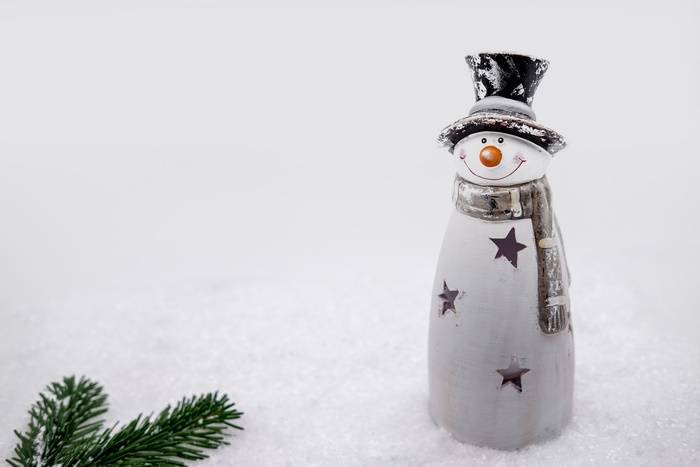 Snowman figurine with Christmas tree branch in snow