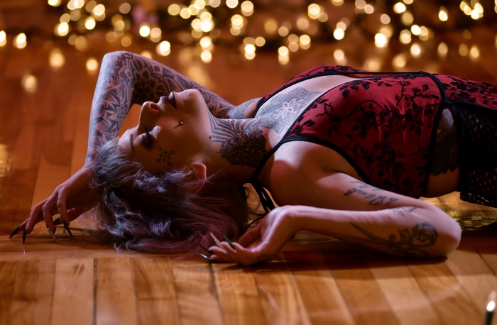 Tattooed woman lying on floor with bokeh lights