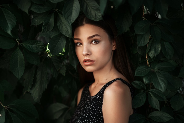 Brunette model portrait among green leaves