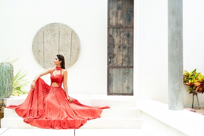 Shilpa Shetty in a red dress sitting on steps