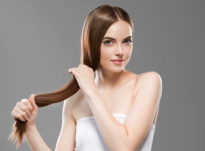 Woman with long brown hair touching her hair