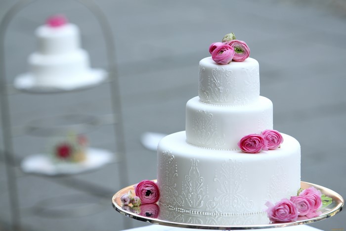 White tiered cake with pink ranunculus flowers