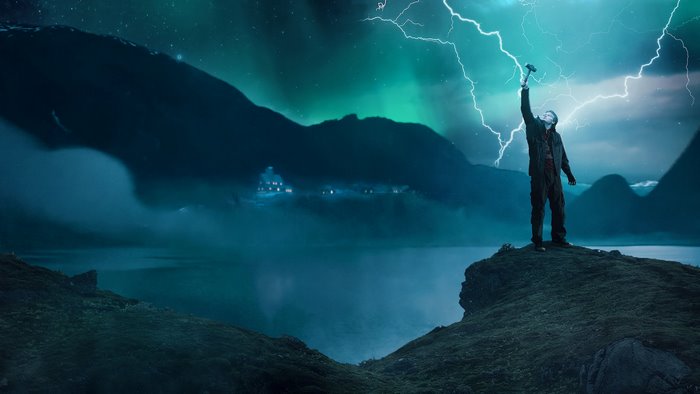 Man with hammer summoning lightning in front of mountains