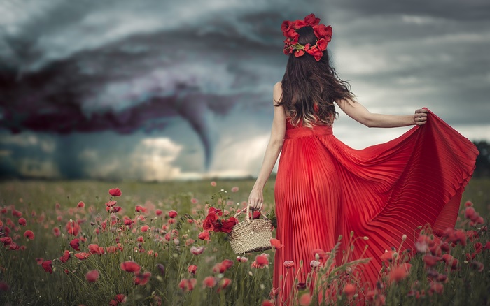 Woman in red dress with poppy wreath in poppy field