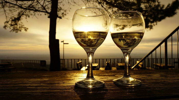 Two glasses of white wine on a table at sunset