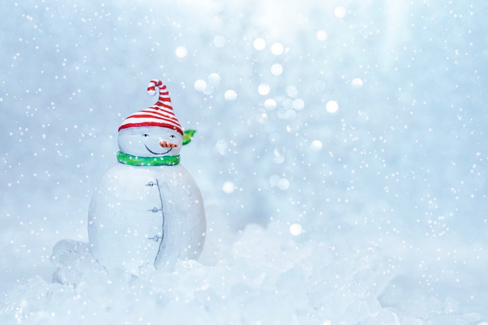 Snowman figurine with striped hat and scarf in snow