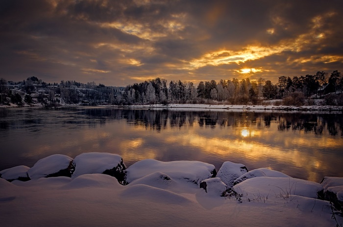 Winter sunset over a Norwegian lake with snow-covered rocks