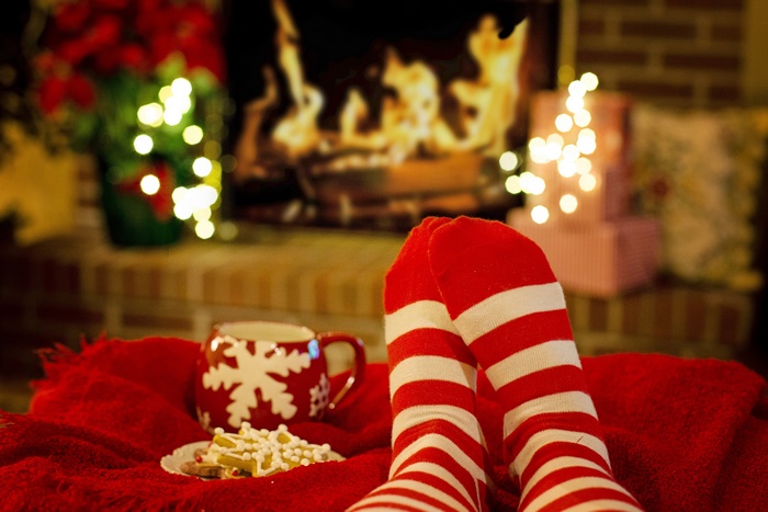 Christmas scene with feet in socks, mug, and fireplace