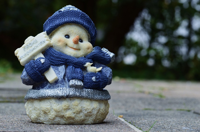 Snowman figurine holding a sign saying Frohe Weihnachten