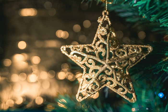 Golden star ornament on a Christmas tree with bokeh