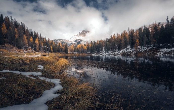 Autumn lake with wooden bridge and mountain in clouds