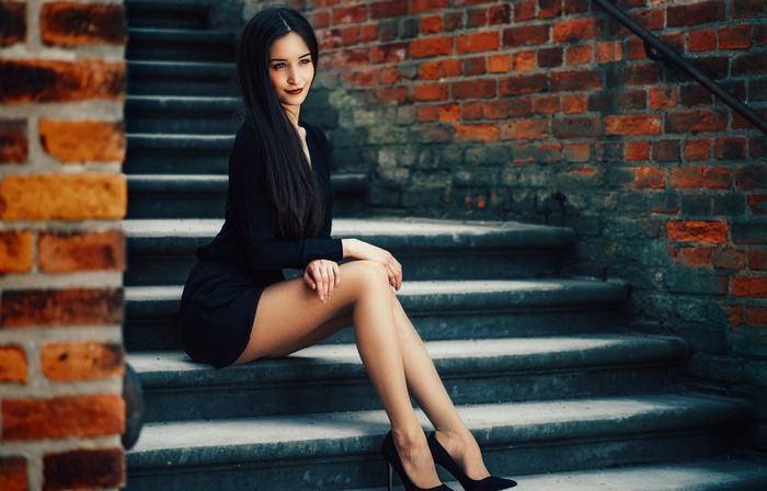 Brunette woman with long hair sitting on stairs