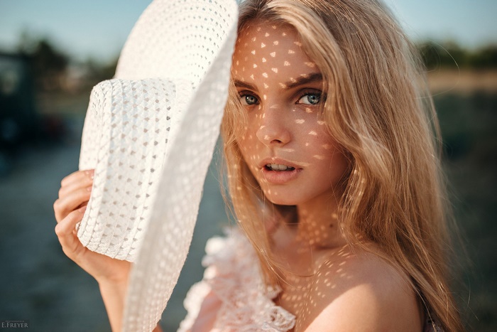 Blonde model wearing a hat with shadows on her face