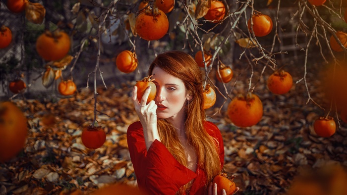 Woman in red dress holding persimmons