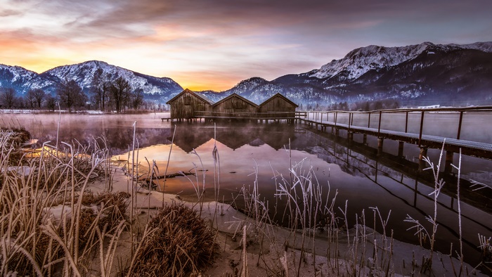 Wooden Boathouses on a Lake with Mountains in Winter