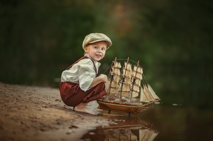 Boy with toy ship by the water