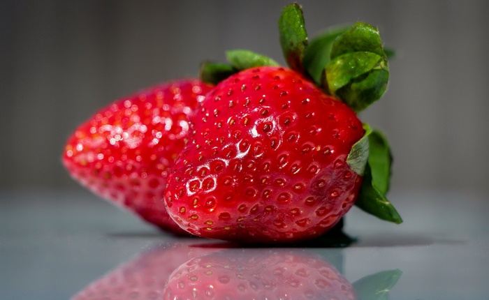 Two ripe strawberries with green leaves