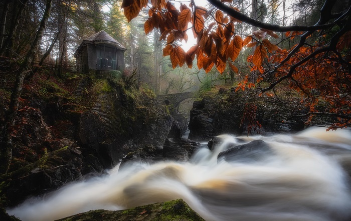 Waterfall and stone bridge in a forest during autumn